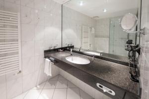 La salle de bains est pourvue d'un lavabo et d'un miroir. dans l'établissement AcarA das Penthouse Hotel, à Oldenbourg