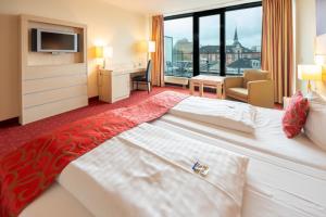 オルデンブルクにあるアカラ ダス ペントハウス ホテルの大きなベッドとデスクが備わるホテルルームです。