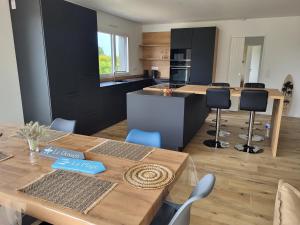una cucina con tavolo in legno e una cucina con armadi neri di Villa Lou Sanaé - Bord de mer - Spa, paddle, Kayak - Classé 4 étoiles a Santec