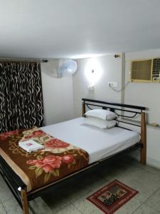a bedroom with a bed with a floral blanket on it at Lake Land Guest House in Kolkata