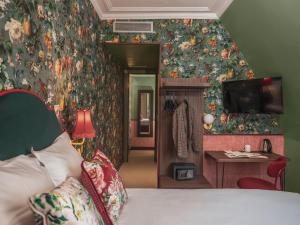 パリにあるオテル ブリッタニーの花で覆われた壁、ベッド付きのベッドルーム1室が備わります。