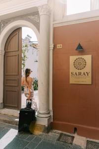 uma mulher de pé com a sua bagagem em frente a um edifício em Saray Monumental Luxury Villa Medieval Town, Rhodes in Ilha de Rhodes
