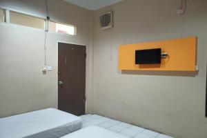 Cette chambre comprend un lit et une télévision murale. dans l'établissement SPOT ON 92648 Wisma Padi Syariah Panyipatan, 