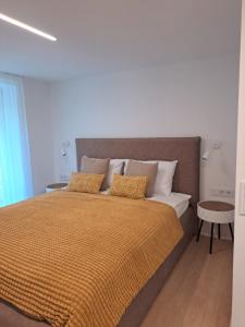 a bedroom with a bed with an orange comforter and pillows at Kurortas Apartments in Palanga