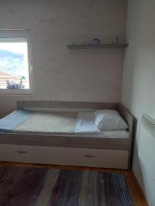 a small bedroom with a bed with a window at Amethyst apartment in Igalo