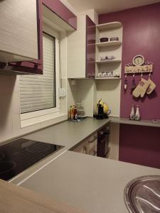 a kitchen with purple walls and a counter top at Amethyst apartment in Igalo