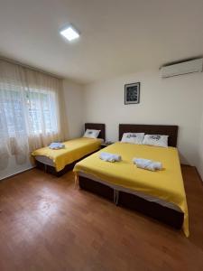 two beds in a room with yellow sheets at Villa Utopia in Star Dojran