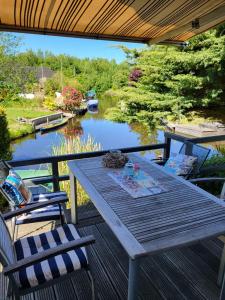 a wooden table on a deck with a view of a river at Ferienhaus Brungers in Südbrookmerland
