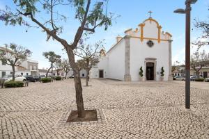 a small tree in front of a church at Ana Townhouse in Tavira