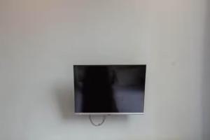 TV de pantalla plana colgada en la pared en OYO 92644 Onong's Homestay en Tomohon