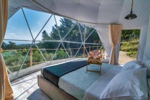 a bedroom with a bed and a large glass window at luxury dome tents ikaria ap'esso in Raches