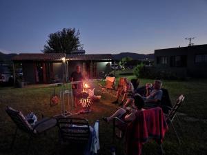 a group of people sitting around a fire in a yard at Sky Cottage in Brits