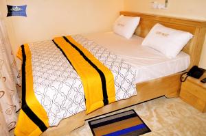 コトヌーにあるGlory Palace Hotelの小さなベッドルーム(黄色と白のシーツが備わるベッド1台付)