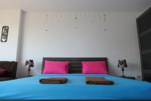 1 dormitorio con cama azul y almohadas rosas en View Talay 1B Studio en Pattaya South