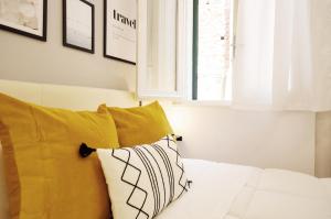 a bed with yellow and white pillows and a window at Central with hydromassage shower and elevator in Perugia +7 photos