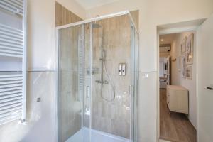 La salle de bains est pourvue d'une douche avec une porte en verre. dans l'établissement VERSILIA MIA - beach at 8min by walk - new rooms!, à Viareggio
