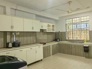 a large kitchen with white cabinets and a window at AaronL Homestay in Kota Kinabalu