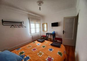 ein Schlafzimmer mit einem Bett mit einer orangefarbenen Bettdecke in der Unterkunft Habitaciones en El Atico de Tona mirando a la Bahia de Santander in Santander