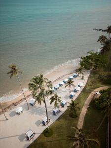 einen Luftblick auf einen Strand mit Palmen und Sonnenschirmen in der Unterkunft Napasai, A Belmond Hotel, Koh Samui in Mae Nam