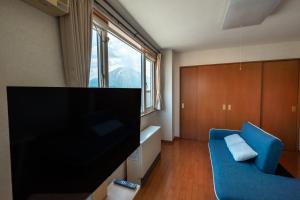 a living room with a tv and a blue couch at Ezo Fujiya Niseko House in Kutchan
