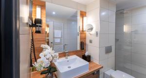 ein weißes Badezimmer mit einem Waschbecken und einem Spiegel in der Unterkunft PLAZA Premium Columbus Bremen in Bremen
