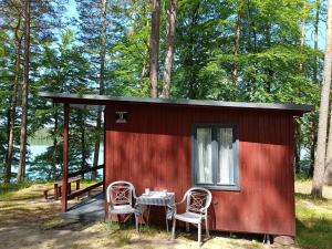 Cabaña roja pequeña con mesa y 2 sillas en Instytut Wypoczynku - domki nad jeziorem Mausz, en Sulęczyno