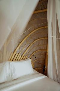 Cama con cabecero de madera y almohada blanca en Kini Resort - Oceanfront Bamboo Eco Lodges, en Sekongkang