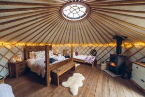 a bedroom in a yurt with a bed and a stove at Scaldersitch Farm Boutique Camping Tipi with private wood fired hot tub in Sheen