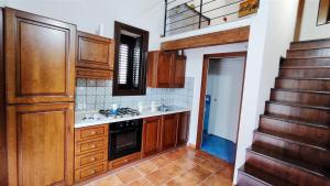 a kitchen with wooden cabinets and a sink and a staircase at Porto Centro Storico Spiaggia Wi-Fi&Self Check-in in Castellammare del Golfo