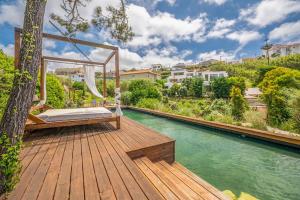 a wooden deck with a bed on top of a river at GuestReady - Luxury Beach Villa with Private Pool in Ericeira
