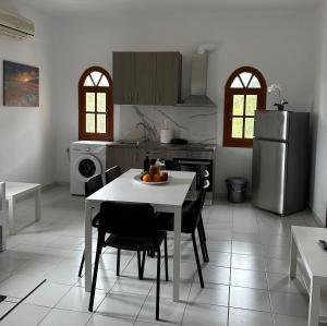 cocina con mesa, sillas y nevera en Flampoura Apartments, en Preveza
