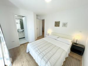 a white bedroom with a large bed and a mirror at Villa Sol Necujam - private pool and 30m from the beach in Nečujam +21 photos