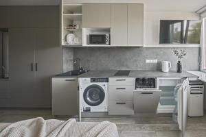 uma cozinha com uma máquina de lavar roupa e um micro-ondas em Mini-Home Apartamentai em Klaipėda