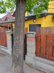 a yellow house with a wooden gate and a tree at Apartmán pri Sokolovni in Martin