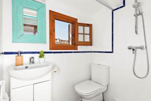ein Badezimmer mit Waschbecken und Toilette und einem Fenster in der Unterkunft Sunset Tirant in Fornells