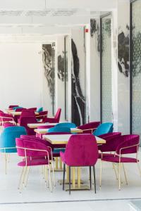 uma sala com mesas e cadeiras com cadeiras roxas em W Regal Boutique Hotel&Spa em Mamaia
