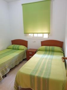 two beds in a room with green and yellow sheets at Costa Caribe III Nº 1108 in Oropesa del Mar