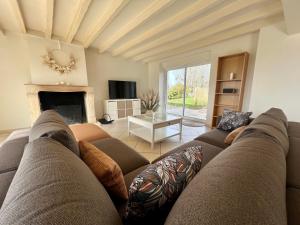 sala de estar con sofá y chimenea en "Villa du Circuit" avec Piscine, 4 Chambres, 4 SDB, à 8 min du circuit, parking et portail électrique, en Mars-sur-Allier