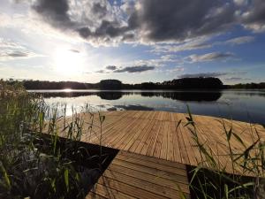 a dock on a lake with the sun setting at Osada Wejsuny in Ruciane-Nida