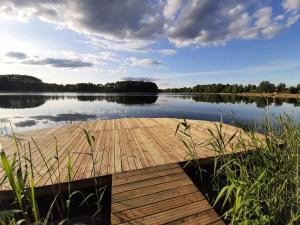 a dock on a lake with a cloudy sky at Osada Wejsuny in Ruciane-Nida