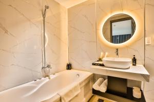 a bathroom with a tub and a sink and a mirror at La Paix Sài Gòn - Boutique Hotel in Ho Chi Minh City