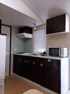 a kitchen with a white refrigerator and a microwave at Camping Derby Loredo in Loredo