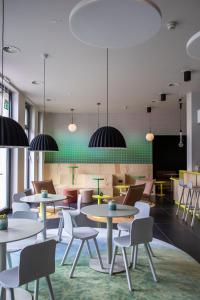 a waiting room with tables and chairs and lights at LyvInn Hotel Frankfurt Messe in Frankfurt/Main