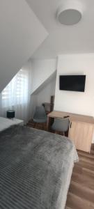 a bedroom with a bed and a desk and a tv at Przystanek Solina in Solina