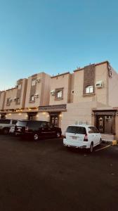 two cars parked in a parking lot in front of a building at شقق الأجواء الفاخرة in Al Madinah