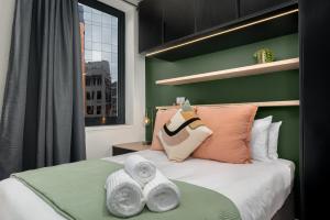 a green bedroom with a bed with towels on it at The Carrington Aparthotel by Totalstay in Cape Town