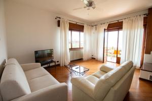 een woonkamer met twee witte banken en een televisie bij Villa Diana - Appartamenti vista Lago in Brenzone sul Garda