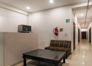 Insight Inn Near Gomti Riverfront Park في Vibhuti Khand: غرفة انتظار مع أريكة وتلفزيون