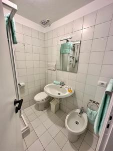 een badkamer met een wastafel, een toilet en een spiegel bij Casa Sabaudia in Turijn
