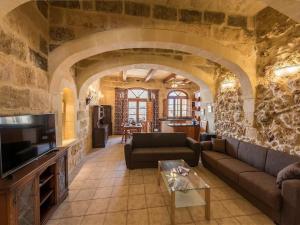 sala de estar con sofá y mesa en Traditional farmhouse with pool, en Xagħra